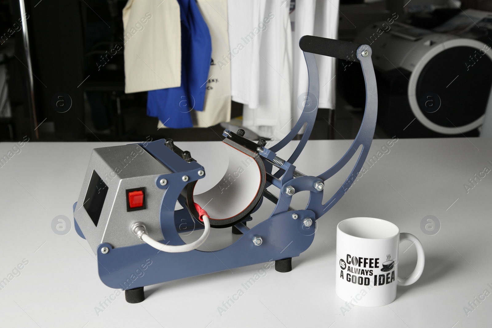 Photo of Printing logo. Heat press and cup on white table