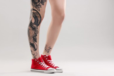 Woman with cool tattoos on grey background, closeup. Space for text