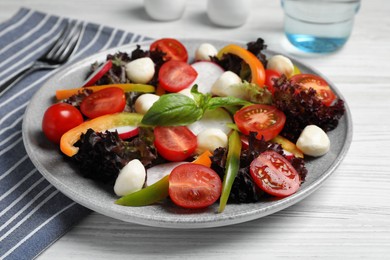 Delicious vegetable salad with mozzarella served on white wooden table, closeup