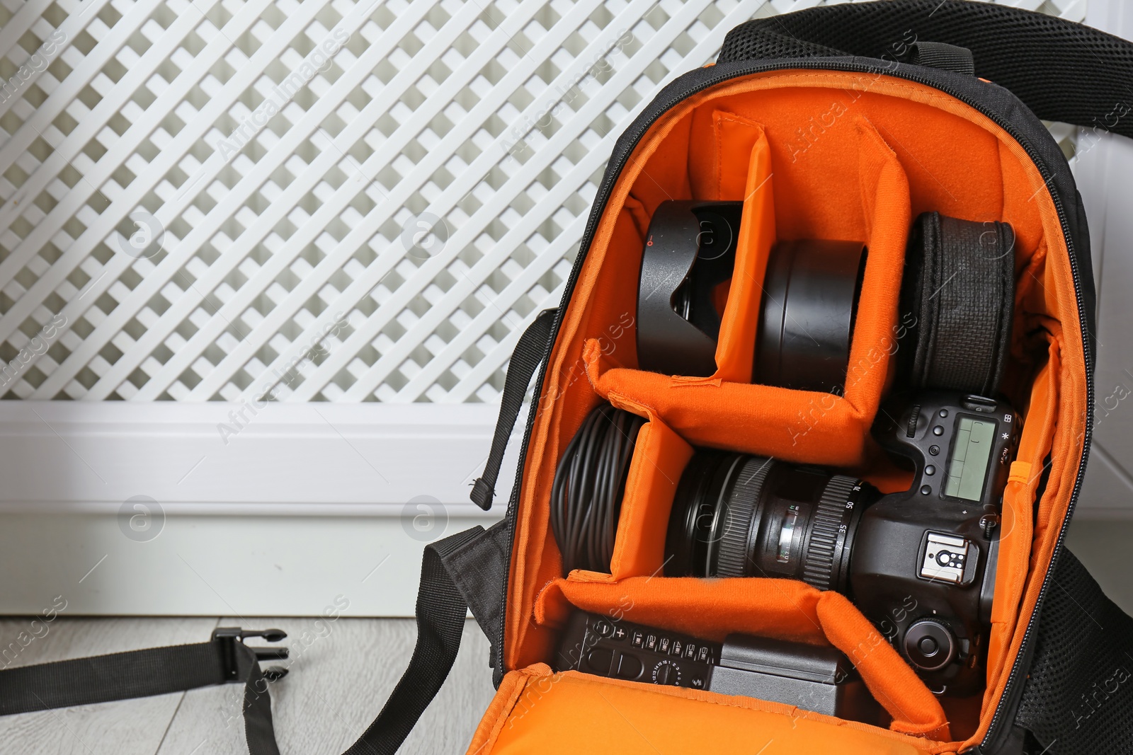 Photo of Bag with digital camera on floor indoors. Professional photographer's equipment