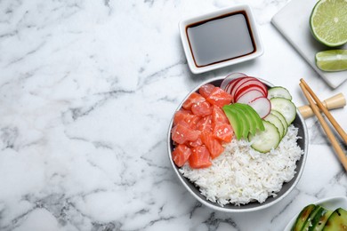 Delicious poke bowl with salmon and vegetables served on white marble table, flat lay. Space for text