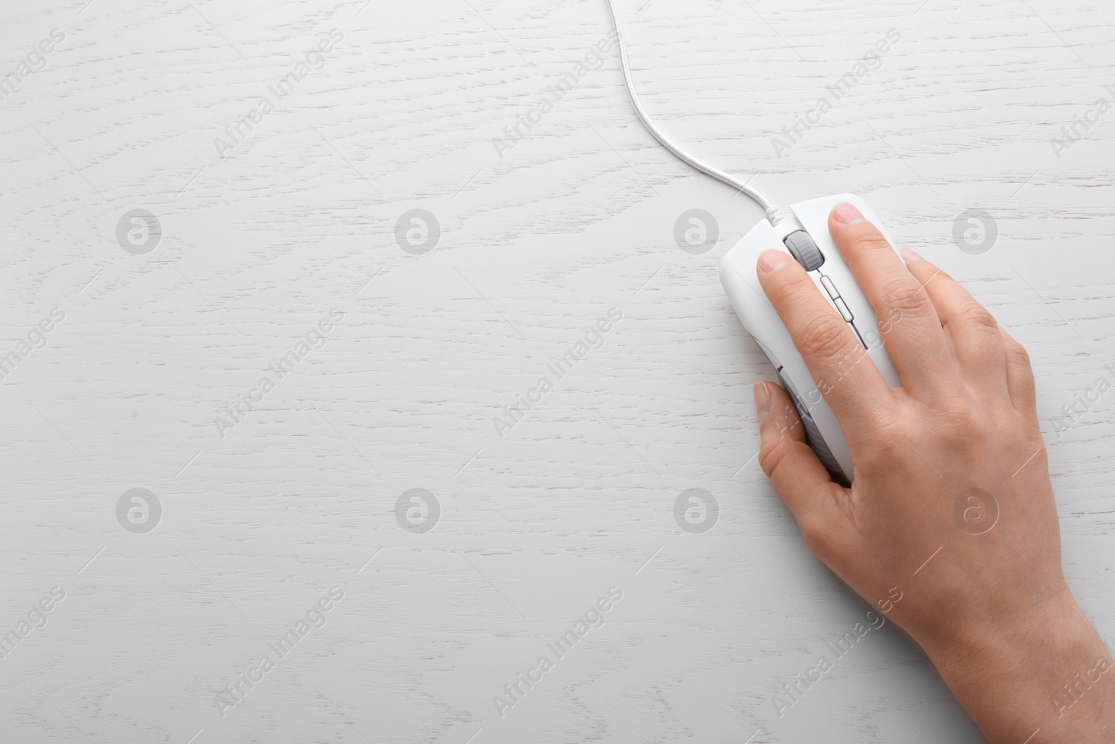 Photo of Woman using computer mouse on wooden background, top view. Space for text