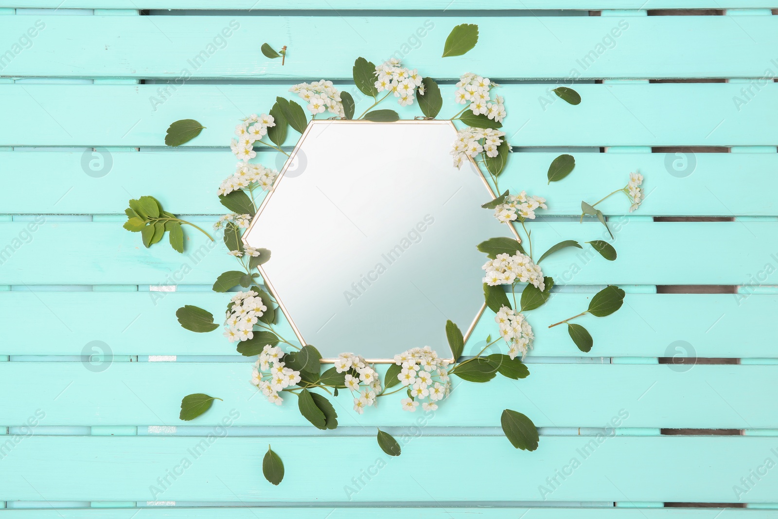 Photo of Mirror decorated with flowers on color wooden background