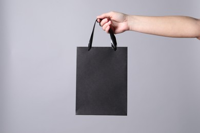 Woman holding paper shopping bag on grey background, closeup