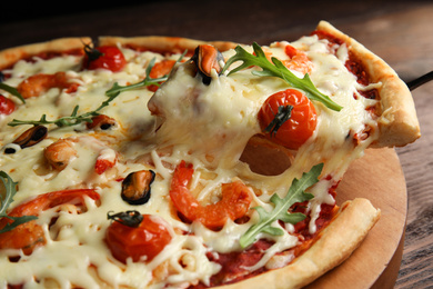 Photo of Delicious seafood pizza on wooden board, closeup