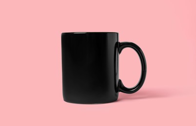 Photo of One black ceramic mug on pink background