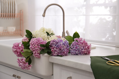 Beautiful bouquet of hydrangea flowers in sink with running water