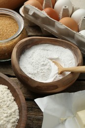 Baking powder and other ingredients for making dough on wooden table, closeup