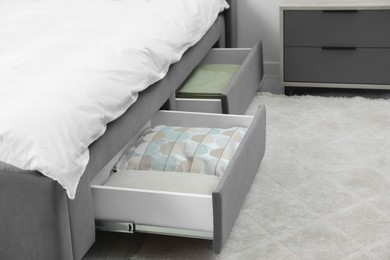 Photo of Storage drawers with bedding under modern bed in room. Space for text
