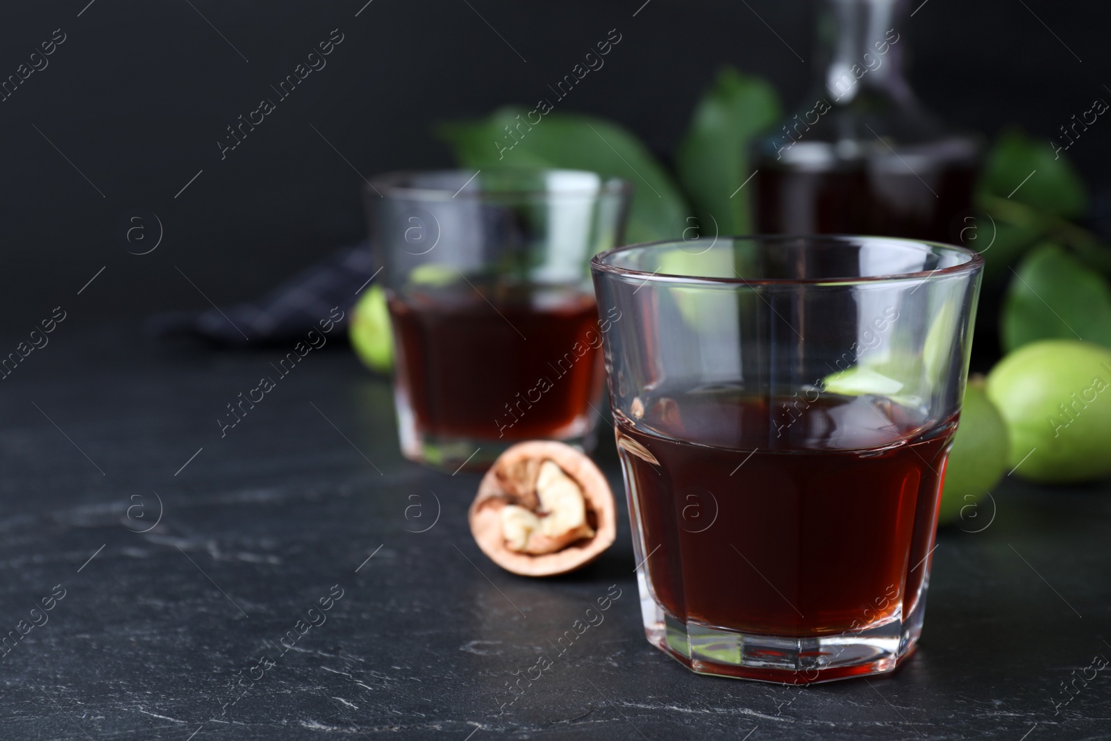 Photo of Delicious liqueur and fresh walnuts on black table. Space for text