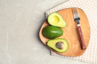 Photo of Board with ripe avocados on grey background, top view