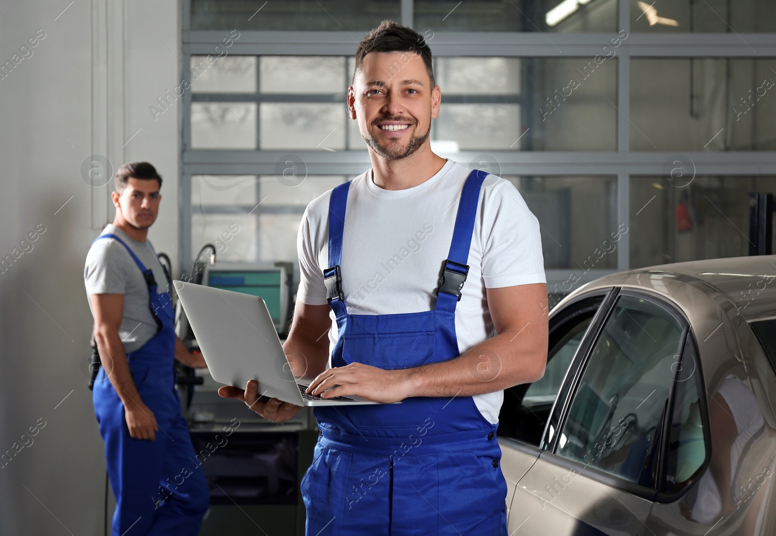 Photo of Mechanic with laptop doing car diagnostic at automobile repair shop