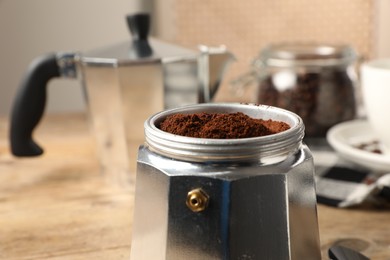 Photo of Moka pot with ground coffee on table, closeup