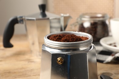 Moka pot with ground coffee on table, closeup