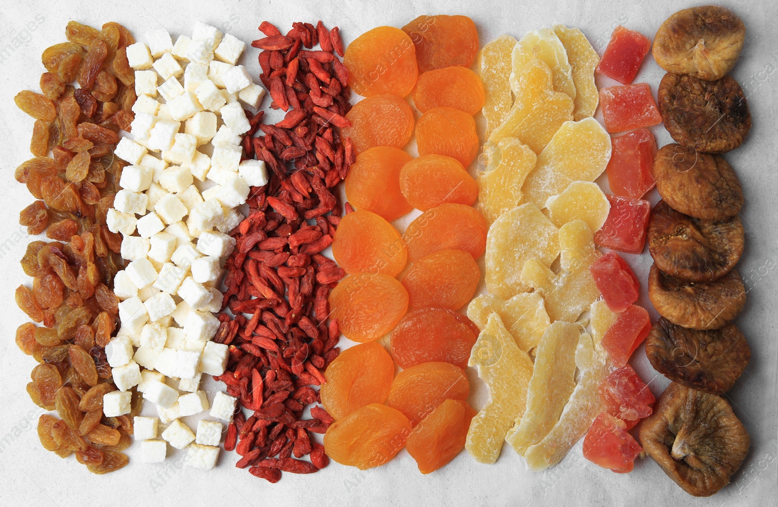 Photo of Different tasty dried fruits on paper, flat lay