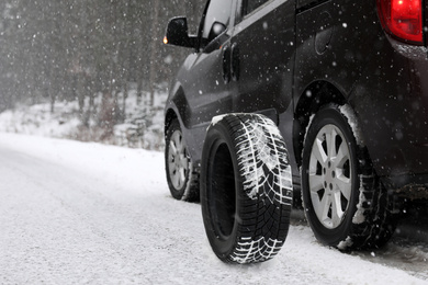 Image of Snow tire near car on road in winter