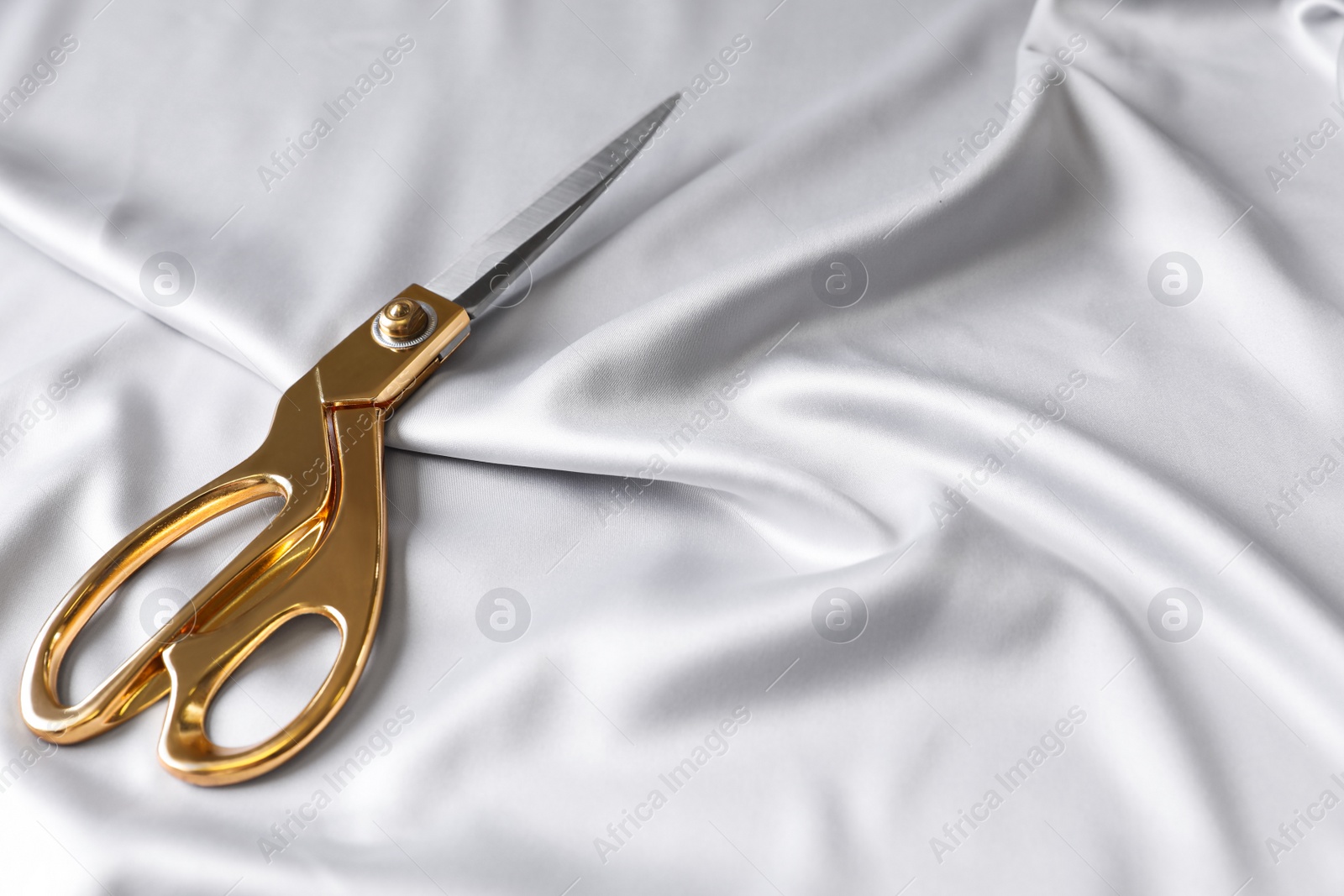 Photo of Scissors on silk fabric. Space for text