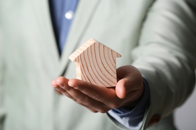 Male agent holding wooden house, closeup. Home insurance