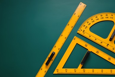 Photo of Protractor, triangle and ruler on green chalkboard, flat lay. Space for text