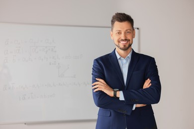 Photo of Happy teacher at whiteboard in classroom during math lesson