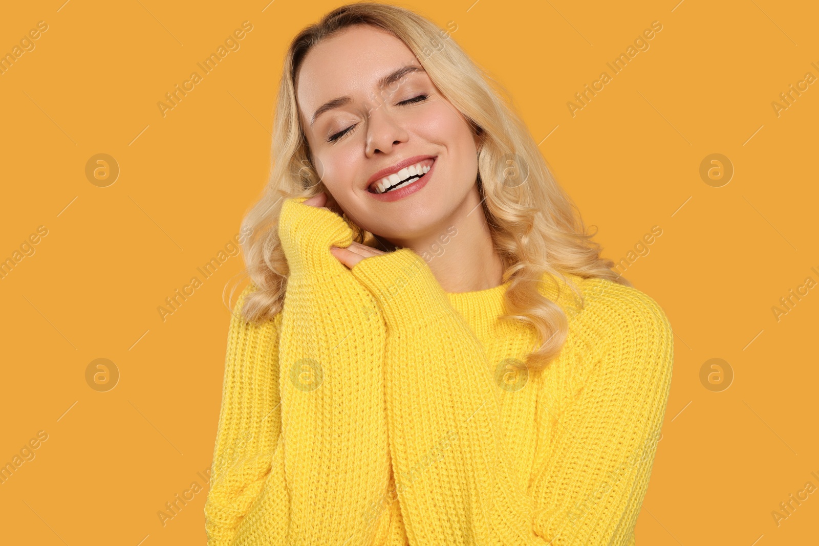 Photo of Happy woman in stylish warm sweater on orange background