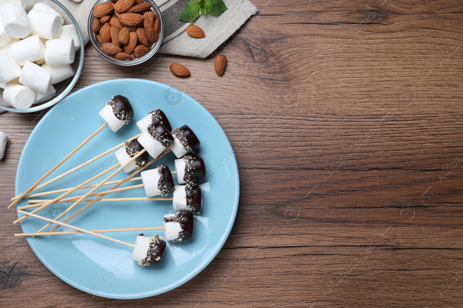 Photo of Delicious marshmallows covered with chocolate on wooden table, flat lay. Space for text