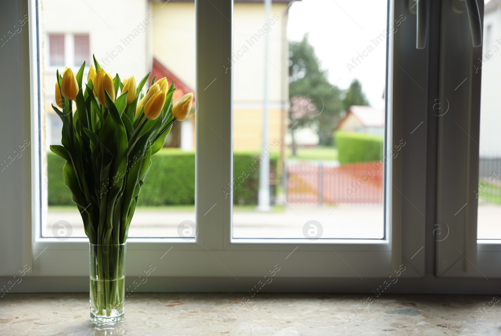 Photo of Bouquet of beautiful yellow tulip flowers in glass vase on windowsill. Space for text