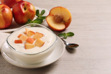 Photo of Delicious yogurt with fresh peach on light wooden table, space for text