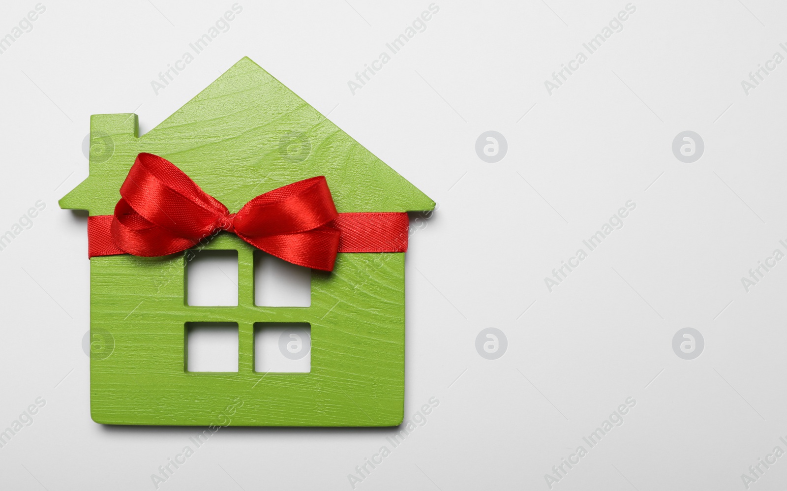 Photo of Wooden house model with red bow on white background, top view. Housewarming party