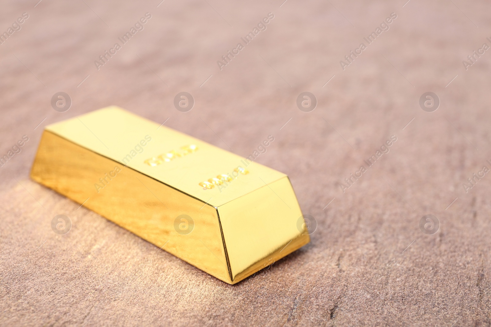 Photo of Shiny gold bar on table, closeup. Space for text