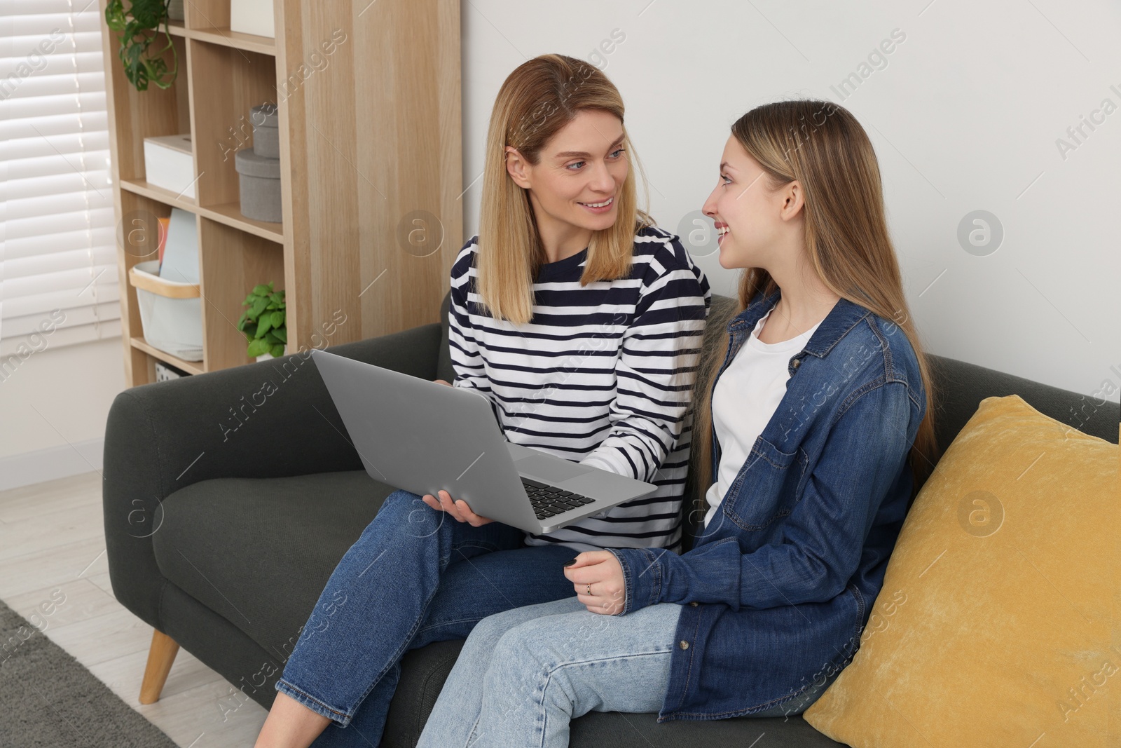 Photo of Happy mother and her teenage daughter with laptop at home