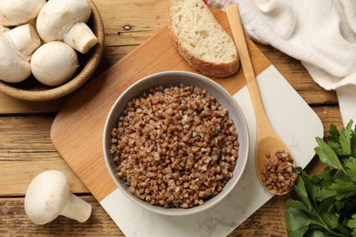 Tasty buckwheat in bowl on wooden table, flat lay