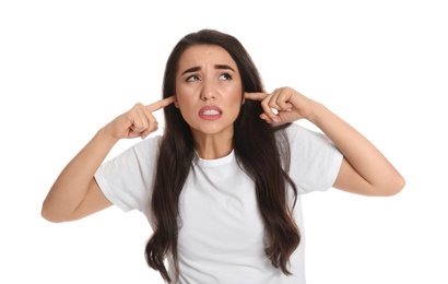 Emotional young woman covering ears with fingers on white background