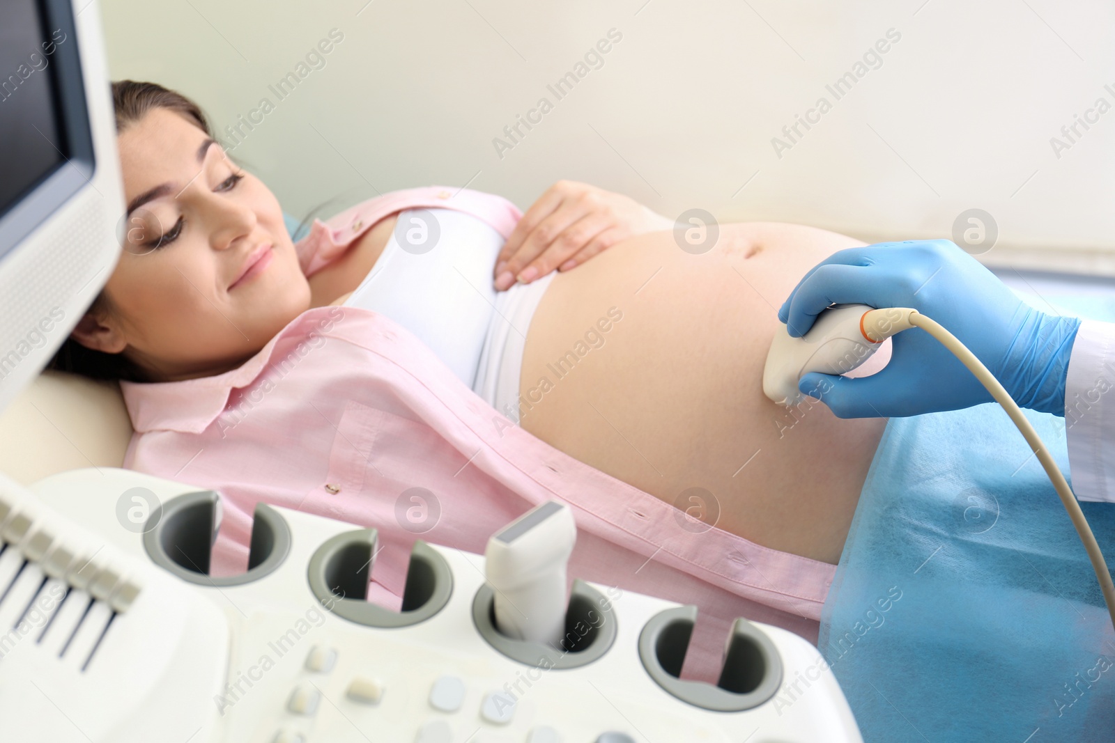 Photo of Young pregnant woman undergoing ultrasound scan in clinic