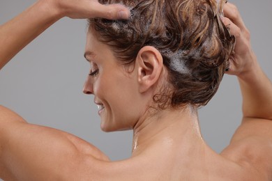 Photo of Woman washing hair on light grey background, back view