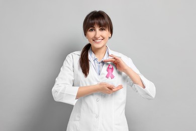 Photo of Mammologist with pink ribbon on light grey background. Breast cancer awareness