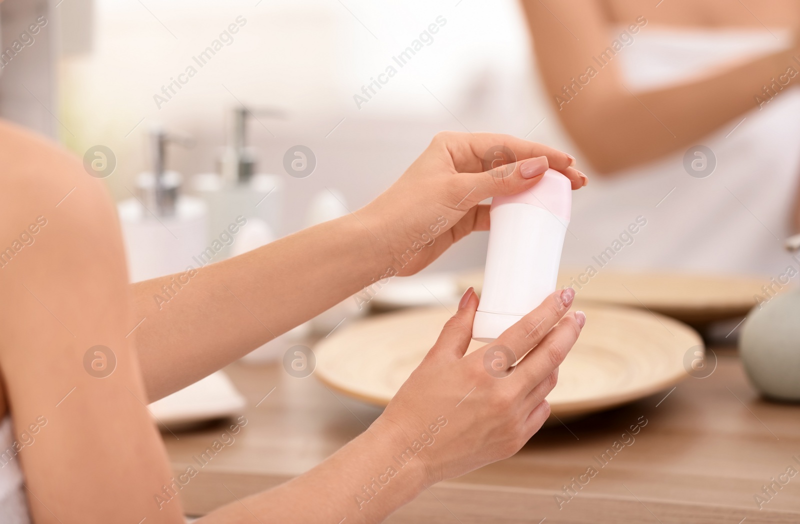 Photo of Young woman holding deodorant in bathroom, closeup