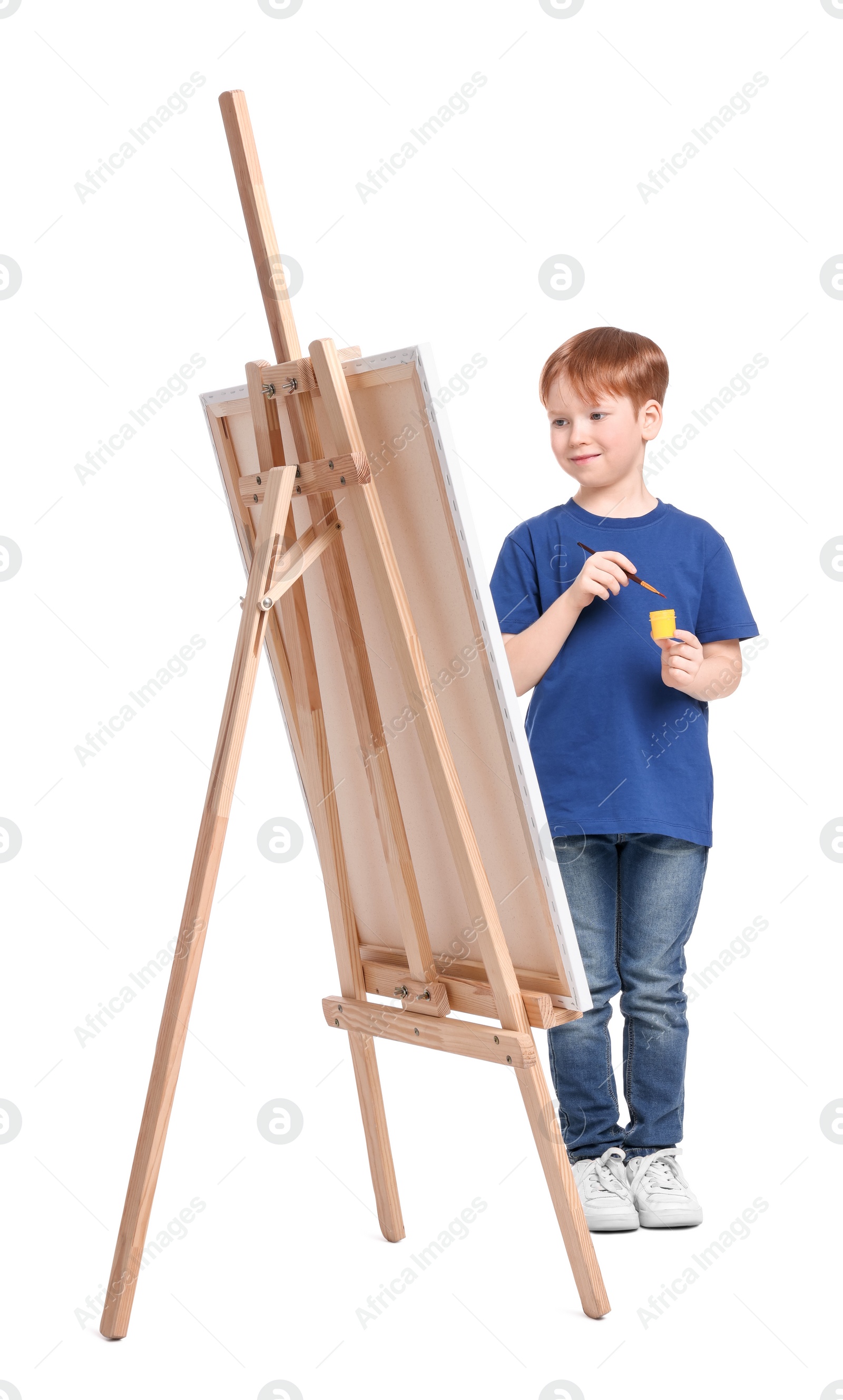 Photo of Little boy painting against white background. Using easel to hold canvas