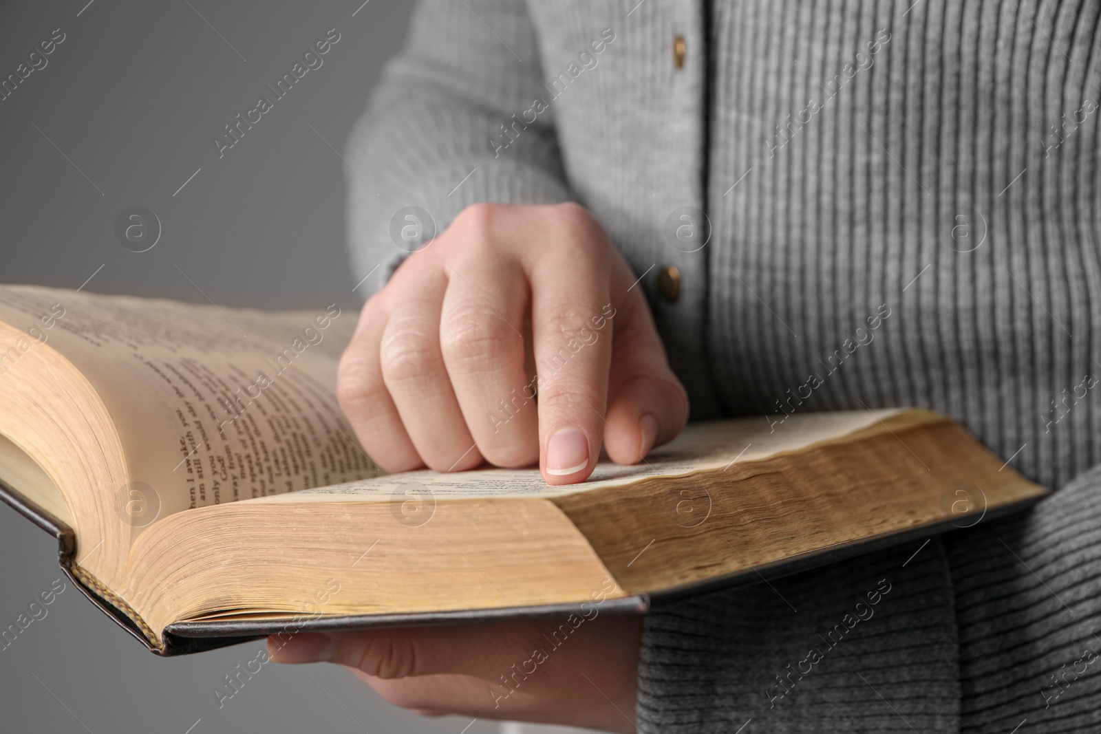 Photo of Woman reading Bible against grey background, closeup