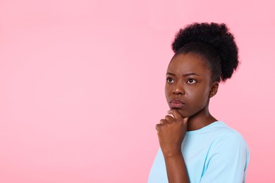 Photo of Portrait of concentrated young woman on pink background. Space for text