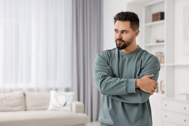 Handsome man in stylish sweater at home, space for text