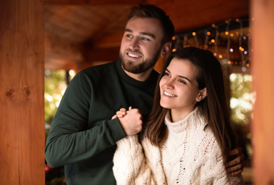 Photo of Happy couple in warm clothes on open terrace. Winter vacation