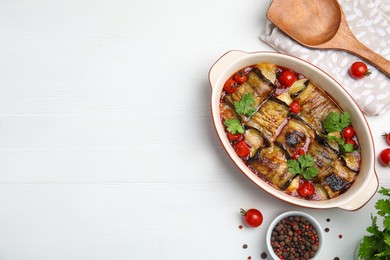 Photo of Tasty eggplant rolls with tomatoes, cheese and parsley in baking dish on white wooden table, flat lay. Space for text