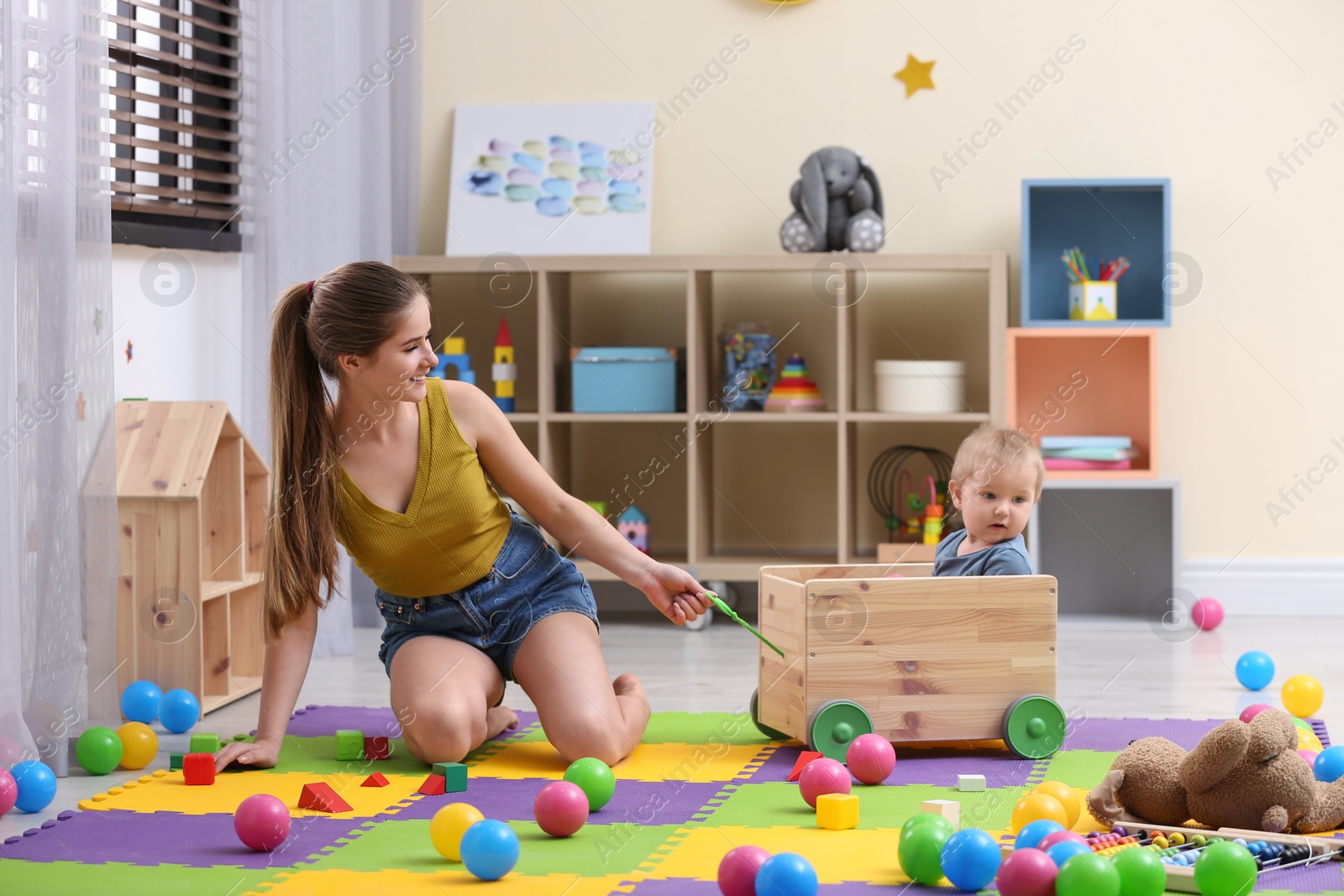 Photo of Teen nanny playing with cute little baby at home