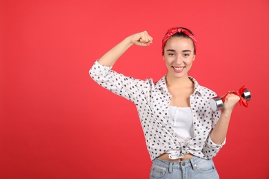 Photo of Woman with dumbbell as symbol of girl power on red background, space for text. 8 March concept