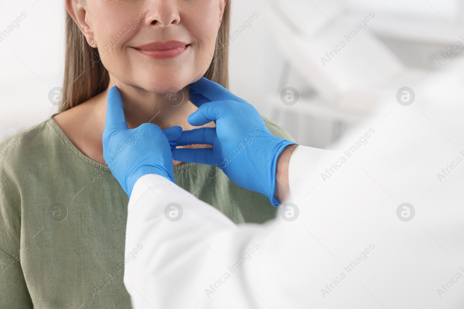 Photo of Endocrinologist examining thyroid gland of patient indoors, closeup