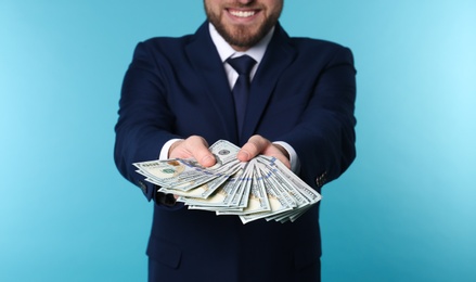 Businessman holding money on color background, closeup