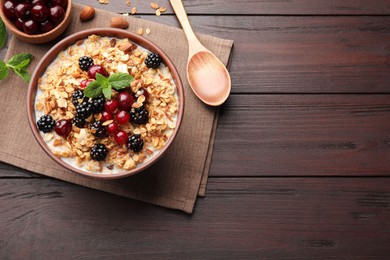 Photo of Bowl of muesli served with berries and milk on wooden table, flat lay. Space for text
