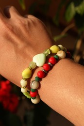 Woman wearing beautiful bracelets with gemstones on blurred background, closeup