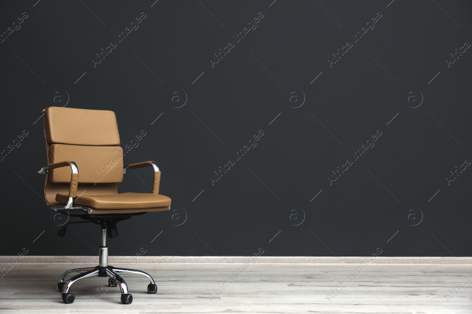 Photo of Comfortable office chair near black wall indoors. Space for text